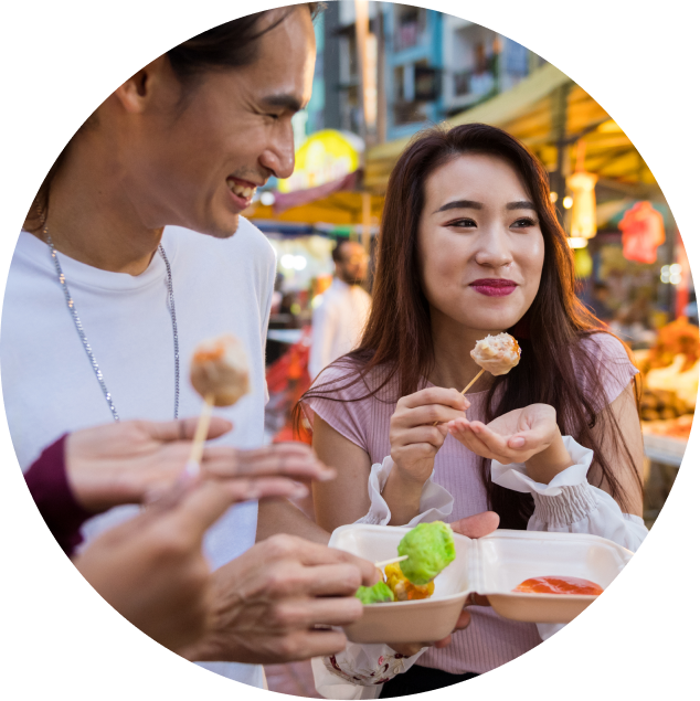 A group of friends huddled together at an outdoor market trying reduced sugar pastries on a stick.